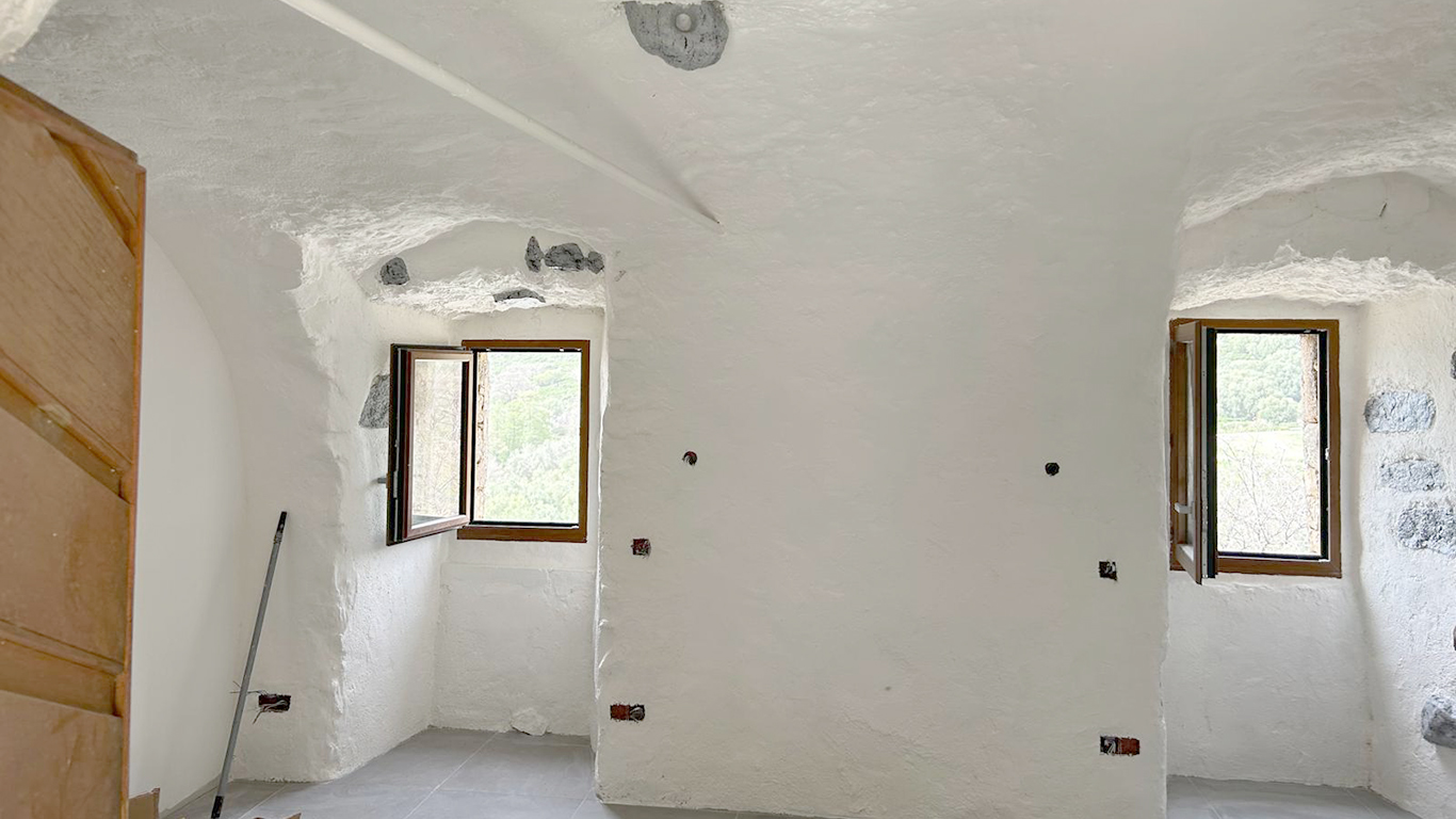 Détail des ouvertures et des menuiseries noires sur l'enduit de façade.