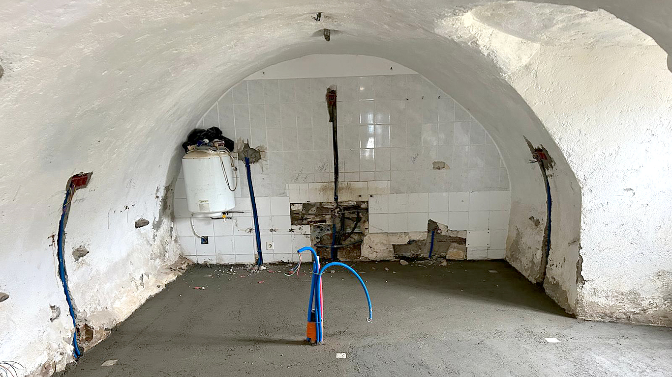 Espace cuisine/buanderie voûté en cours de préparation : dalle de sol coulée et préparation des arrivées d'eau.