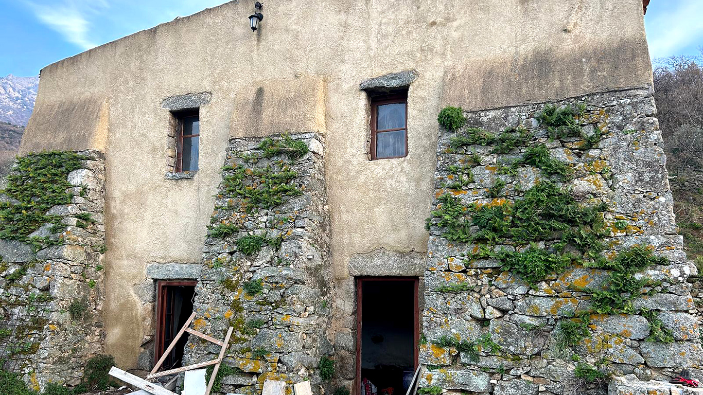 Façade extérieure du Pagliaghju avant la rénovation complète, montrant les pierres et la végétation.