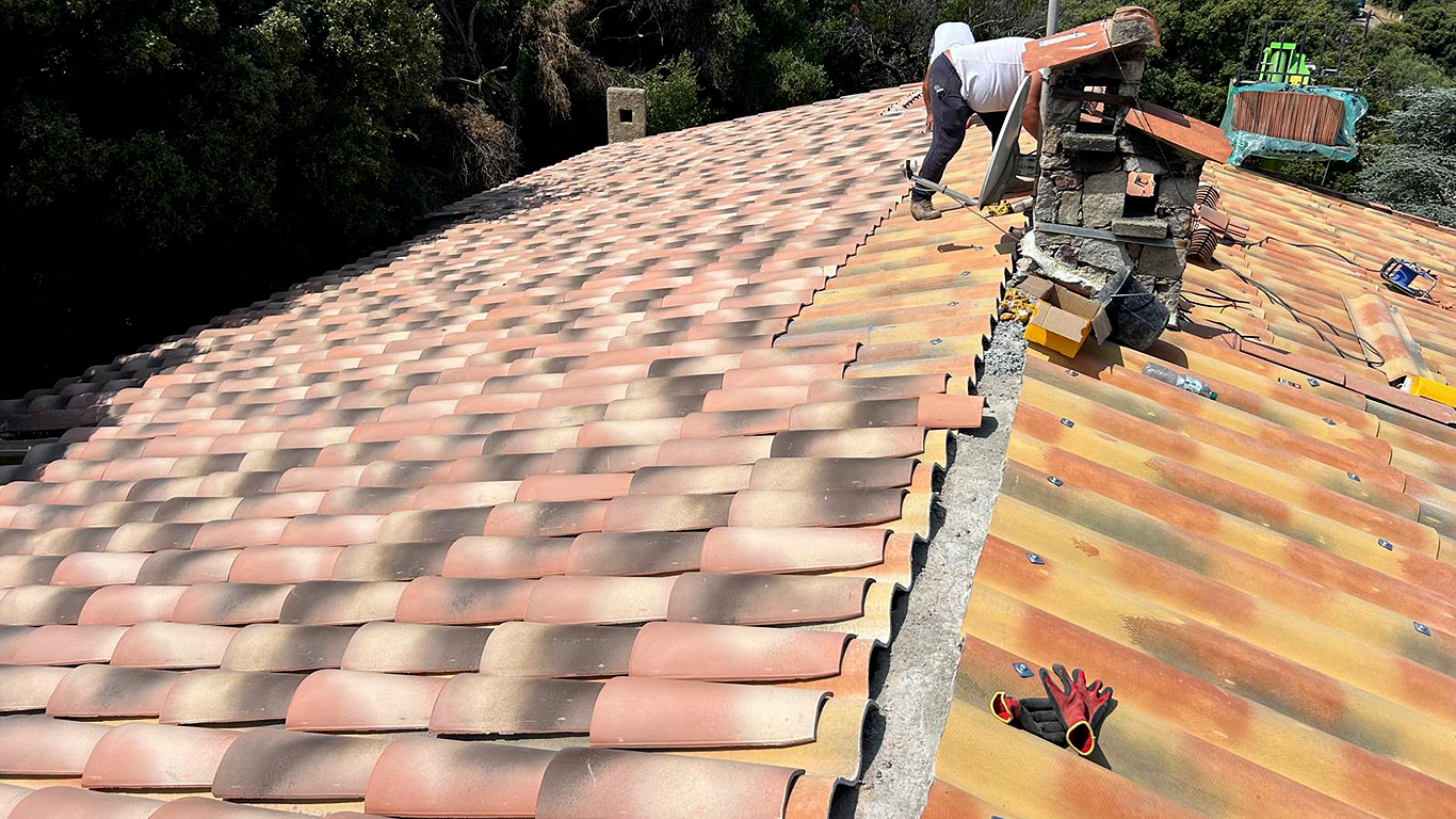 Pose des nouvelles tuiles sur le faîtage, à proximité de la cheminée.